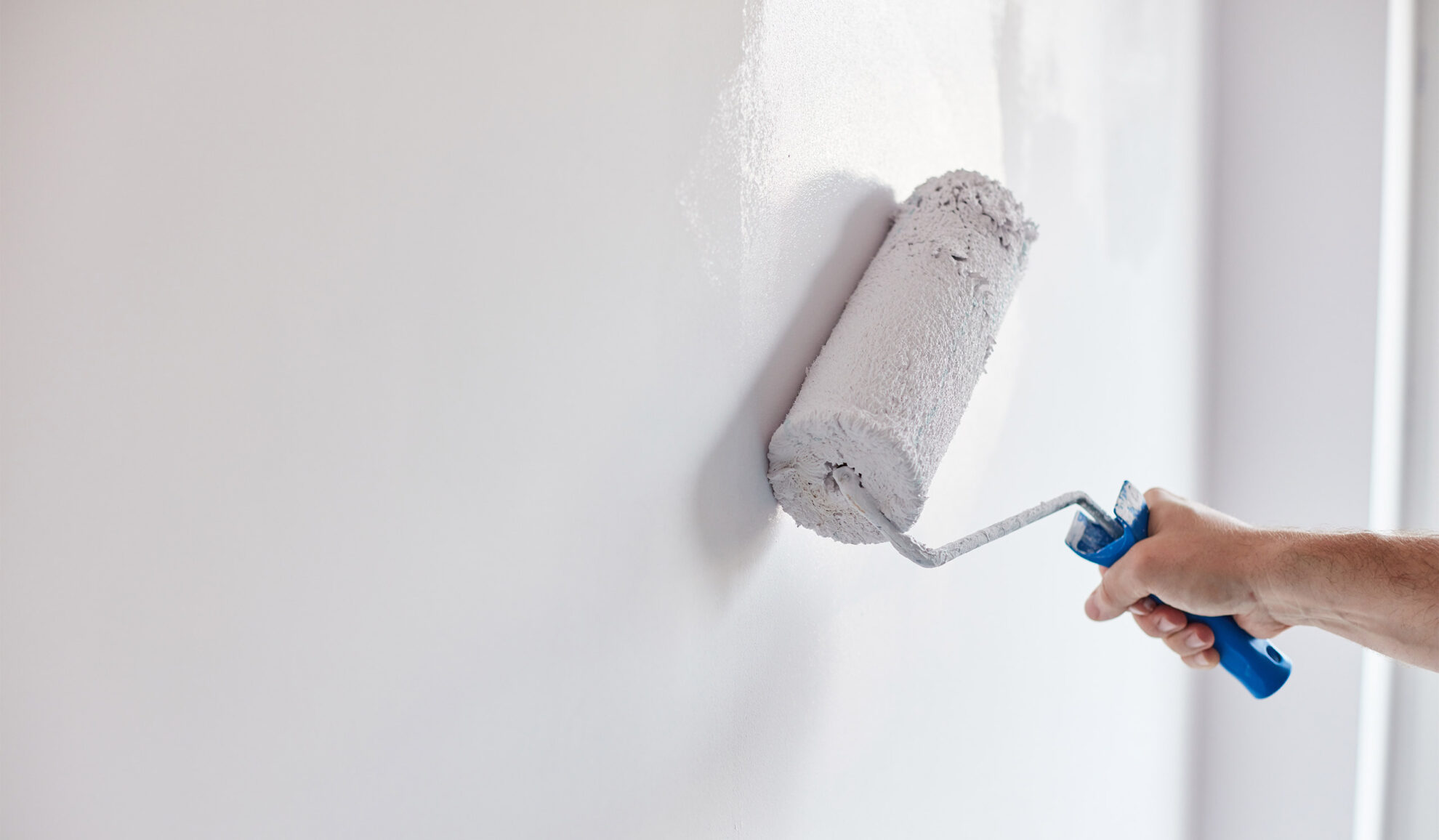contractor hand close up painting interior white wall with paint roller bellbrook oh
