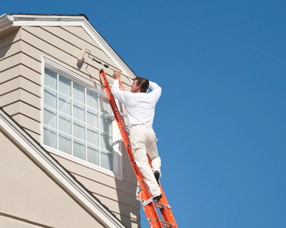 man in white painting the siding of a house bellbrook oh